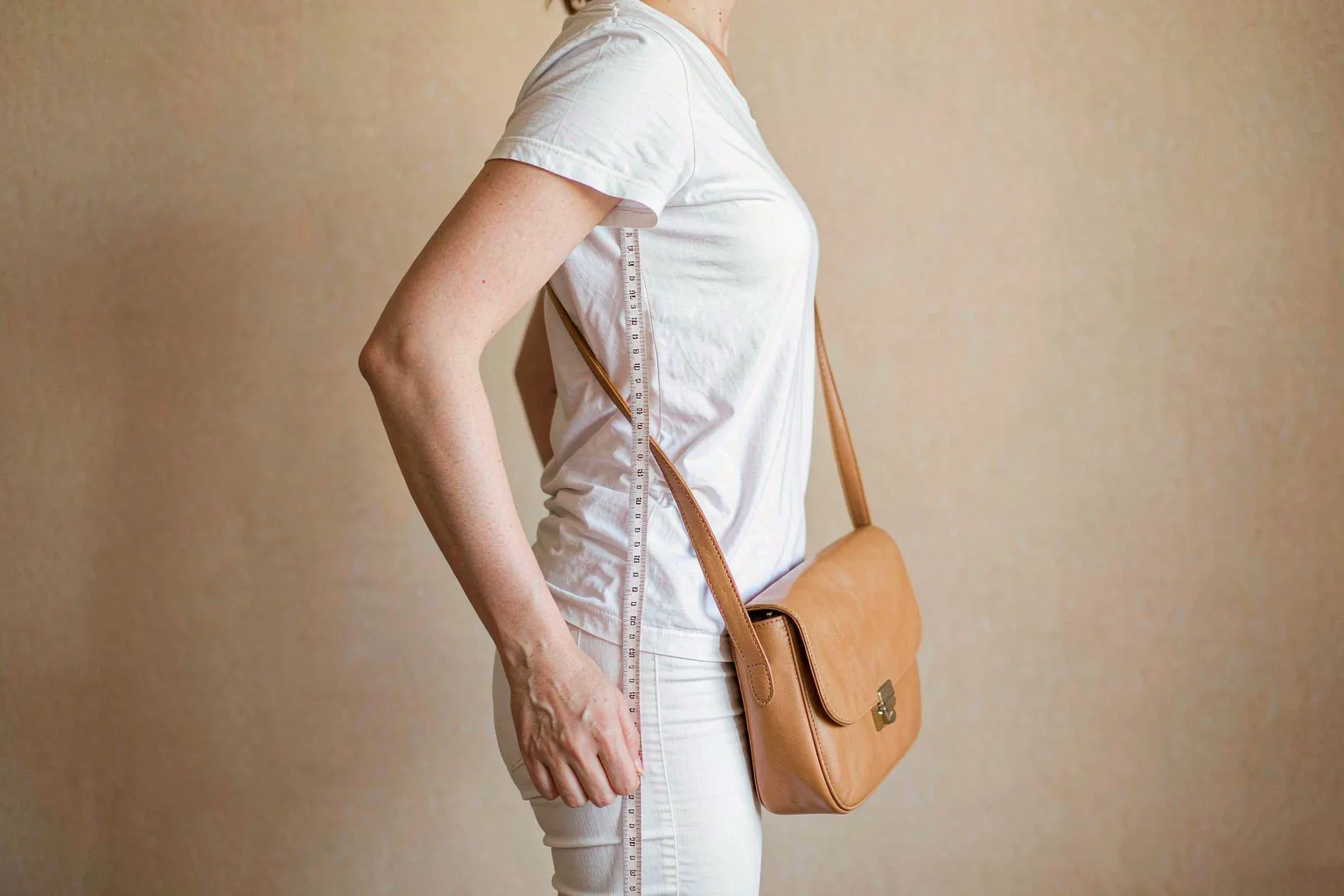 Measuring a handbag strap drop from the crook of the elbow down to the hip with a tape measure