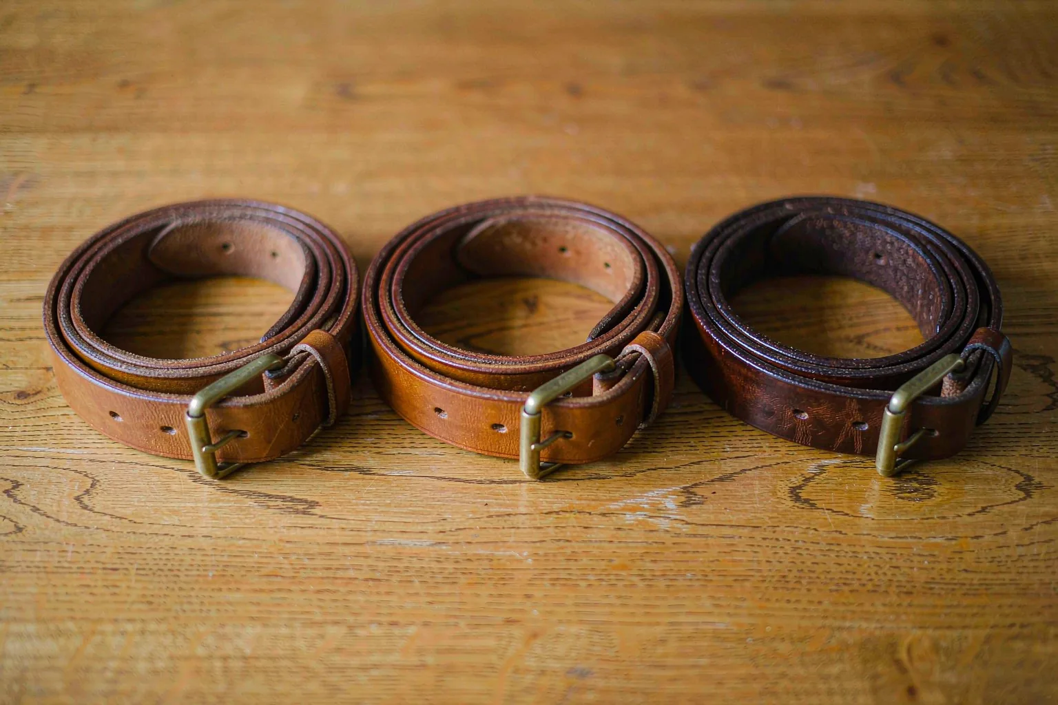 Three vegetable-tanned leather belts showing patina development at one month, one year, and three years